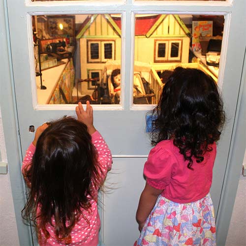 2 children looking through door at a home